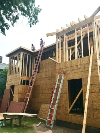 Duplex-Konstruktion auf der Rückseite des Hauses mit Männern auf dem Dach