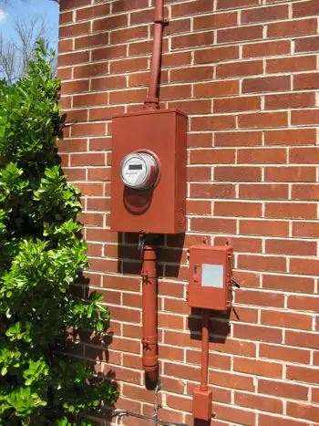 Caja de servicios públicos del medidor eléctrico pintada de rojo para combinar con el rojo ladrillo de la casa