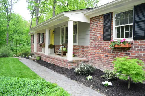 Devant un ranch moderne en brique avec colonnes de porche et jardinières