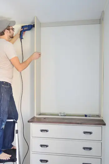 Homem enroscando na lateral de uma estante DIY caseira