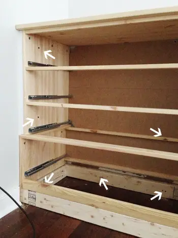 Nuolet osoittavat ruuveihin, joihin Ikea Fjell Dresser kiinnitettiin seinään ja 2x4 alustaan