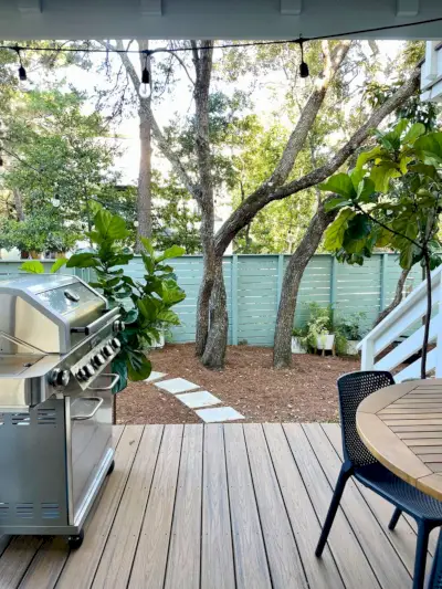 Vertikal utsikt fra dekke terrasse med grill og bord med utsikt over grøntområder i hagen