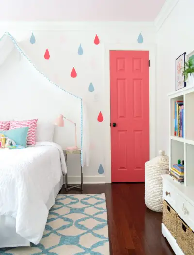 Dormitorio colorido para niñas con gotas de lluvia y puerta rosa en paredes simplemente blancas