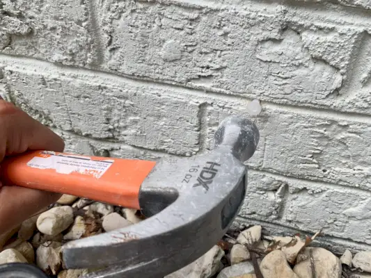 Marteler une ancre dans un mur de briques pour un treillis de vigne