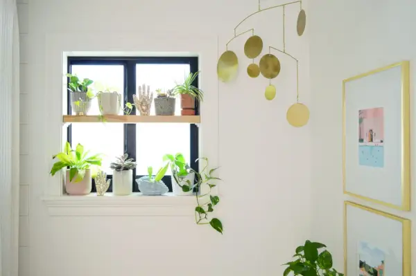 Étagère à plantes en bois dans la salle de bains avec mobile doré