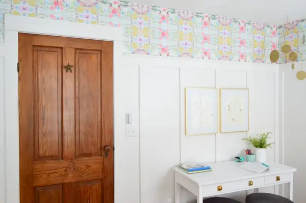 Porta di legno in camera da letto con carta da parati colorata a buccia e bastone sopra il bordo e la stecca