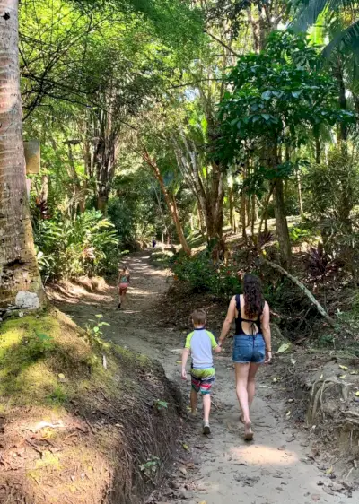 Mor går med små barn til den hemmelige stranden Playa Biesanz i Costa Rica