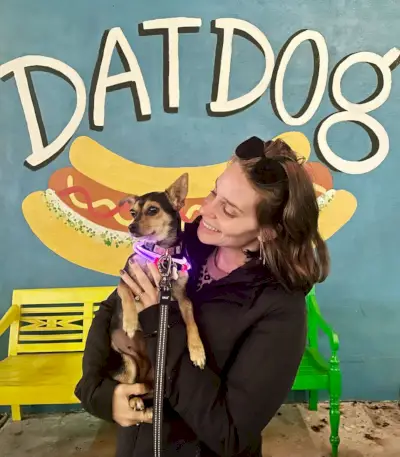 Sherry tiene in braccio un chihuahua davanti al murale del cane Dat di New Orleans