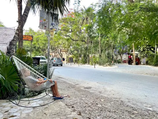 Criança sentada em uma cadeira de balanço perto da estrada em Tulum, México