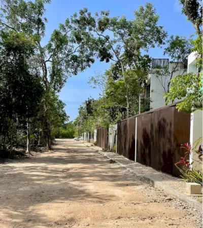 Calle sin pavimentar con casas cerradas en La Veleta Tulum México