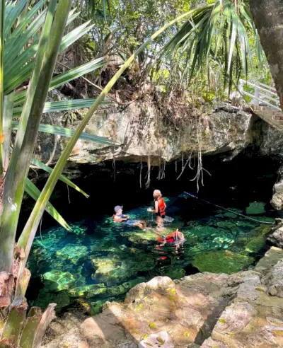 Família nadando sob a caverna no Cenote Cristalino em Akumal, México