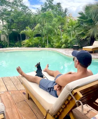 John sentado junto a la piscina en Akumal con Penny The Dog