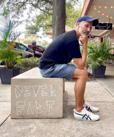 John sitzt auf der Bank „Never Furz“ in Sankt Petersburg, Florida